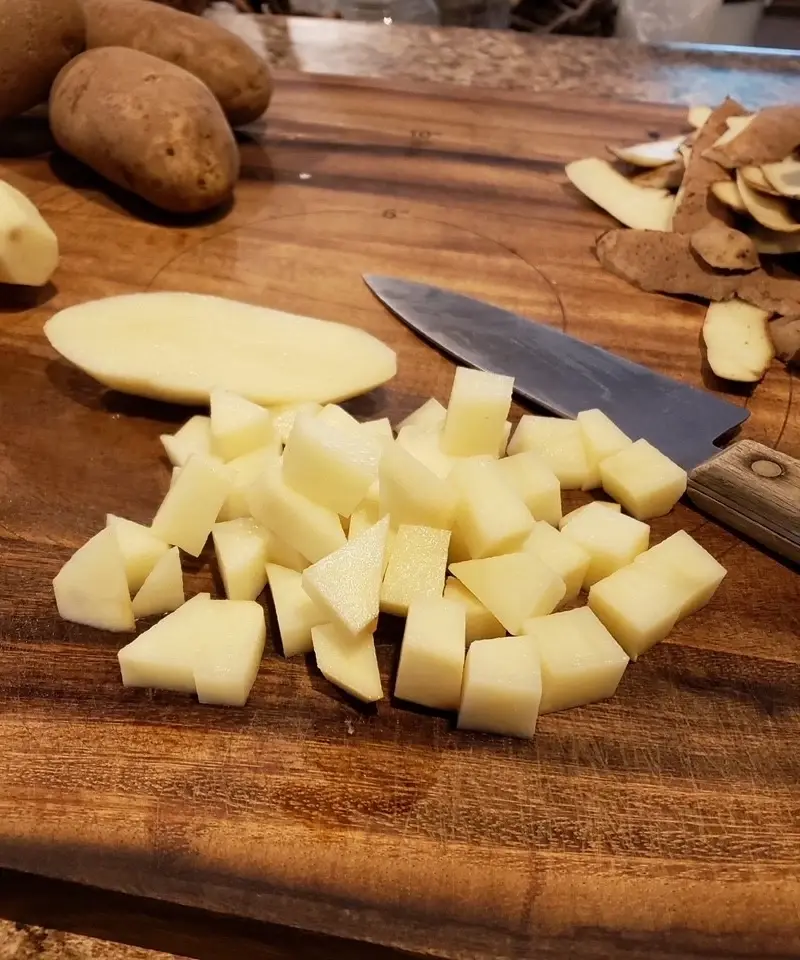 Diced potatoes on a cutting board getting ready to be boiled for a classic old-fashioned potato salad with creamy cooked dressing