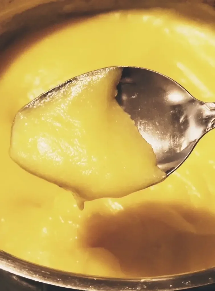 A spoon showing the thickness of the cooked dressing for a classic old-fashioned potato salad with a creamy cooked dressing