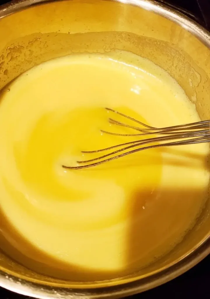 A pot on a stove with cooked dressing for a classic old-fashioned potato salad