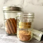 Jar of homemade apple pie spice mix with a rustic farmhouse feel, ideal for adding cozy fall flavor to seasonal recipes.