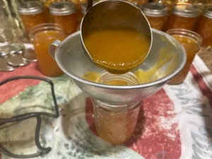 peach butter being ladled into clean jars