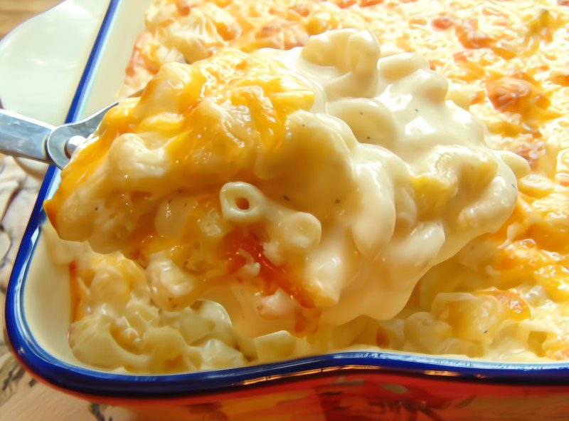 a spoonful of creamy Mac and cheese being lifted out of casserole